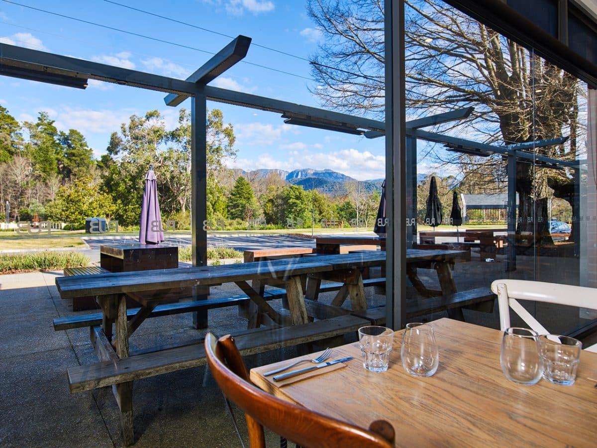 The cosy interior of the Porepunkah Pub, featuring a fireplace and large windows with views overlooking Mount Buffalo
