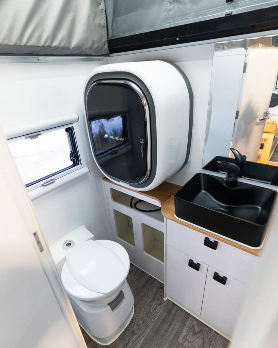 A toilet, washing machine, open shelving, mirror and a black square sink within Arctic Glacier 14TS footprint