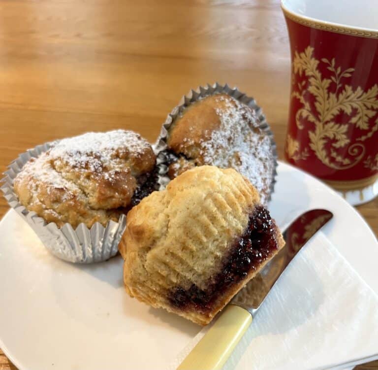 Two easy bake Jam Doughnuts rest on white plate and a knife