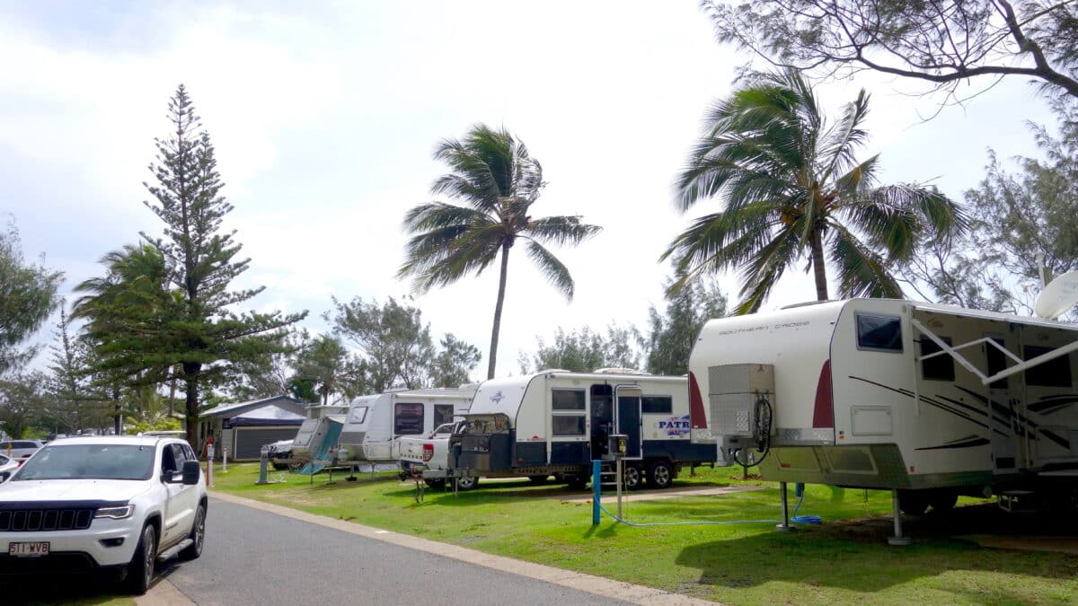 Backing in strong. An uncoupled sunland caravan neatly parked on a grassy green campsite. Near it, a Jeep tow vehicle. A safe towing combination offering enough payload.