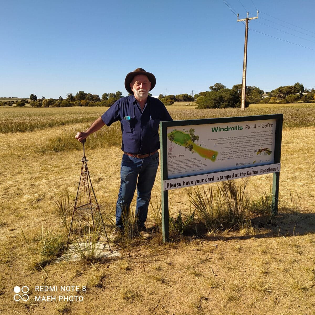 Peter Huth stands at mini windmill and signage at the windmills hole in SA on the Nullarbor Links golf course