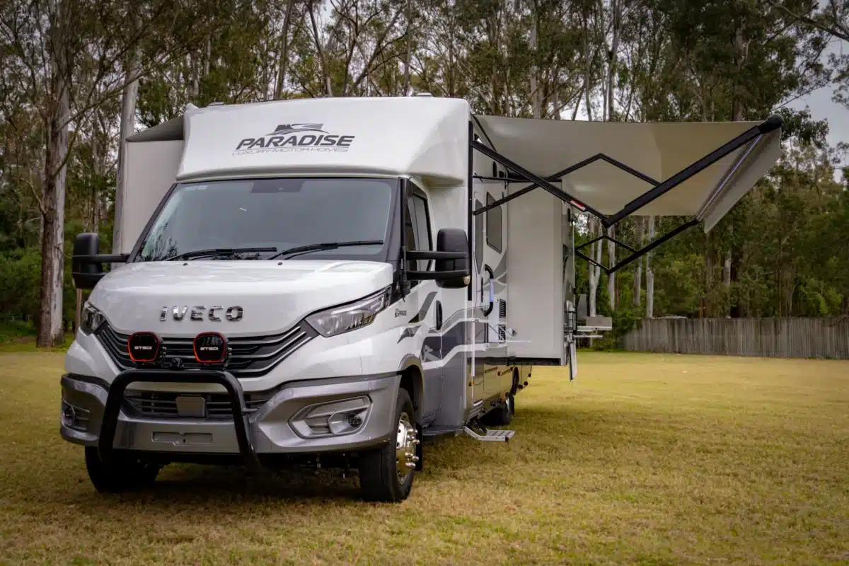 Front view of the Paradise Independence Platinum motorhome with awning deployed at camp
