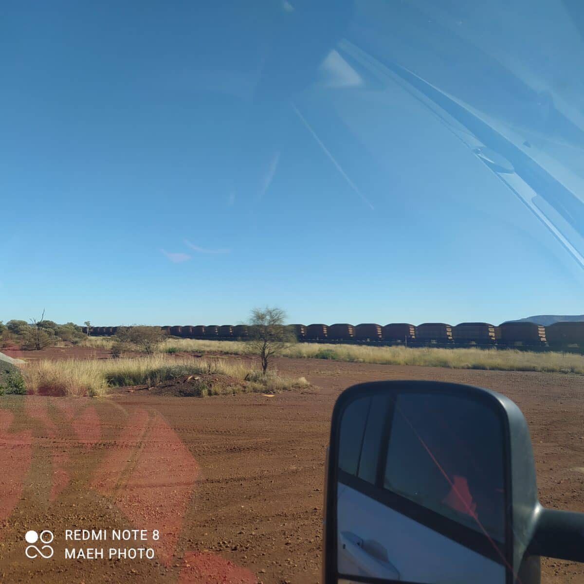 A long Rio Tinto iron ore train stretching across the dry red landscape of the Pilbara.