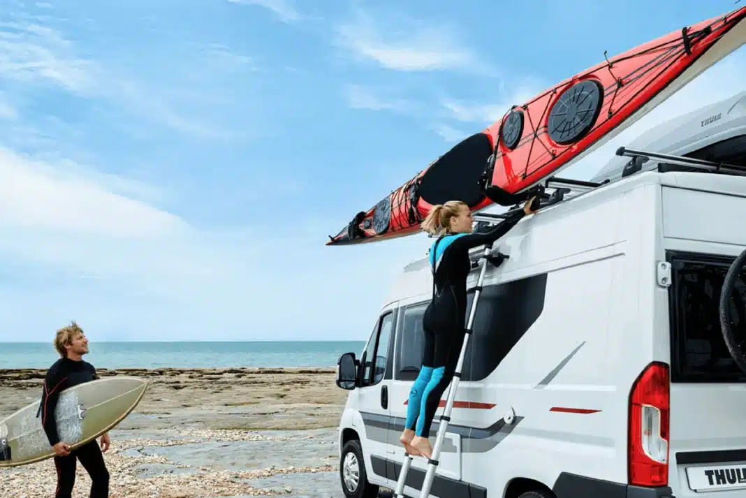 Surfers strapping kayak to van with Thule Hullavator