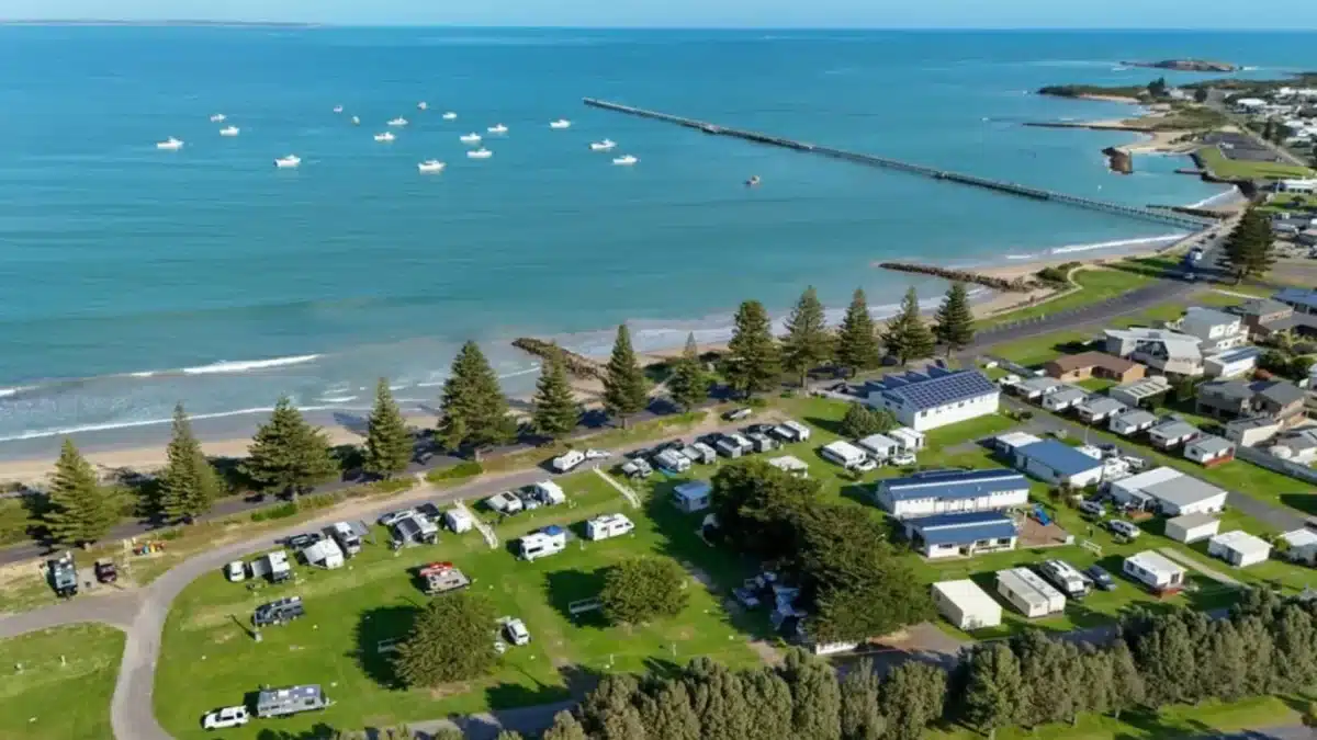 Aerial view of a coastal holiday park in Australia with caravans and camping sites near the ocean
