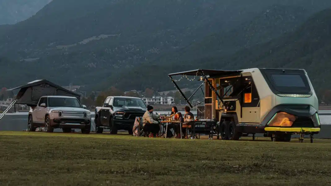 evotrex-pg5-power-generating-rv-trailer-off-grid-camp-setup Evotrex PG5 power-generating RV trailer set up off-grid with vehicles and outdoor camp area
