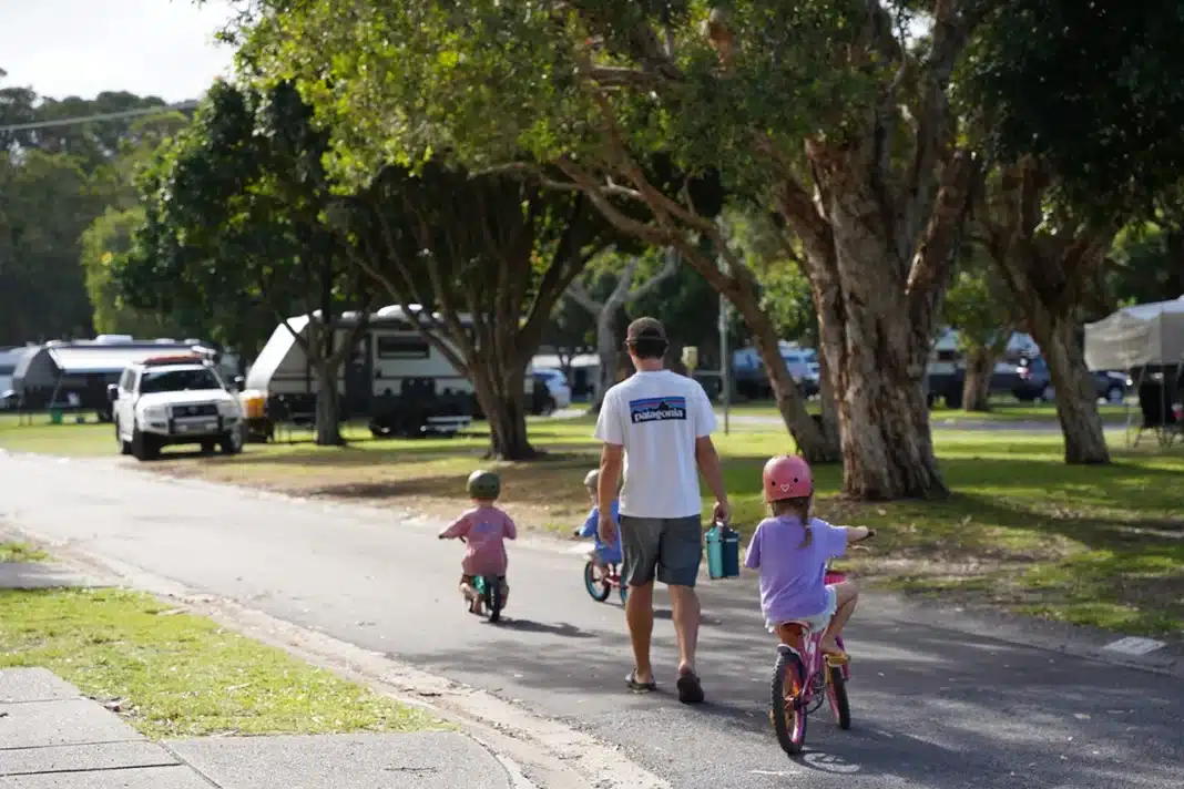 family-walking-through-caravan-park Family walking through a caravan park while children ride bikes