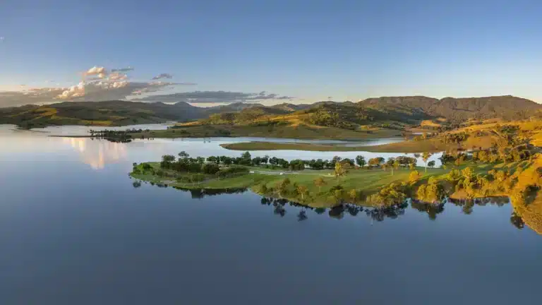 Lakeside camping area at Lake St Clair NSW surrounded by rolling hills