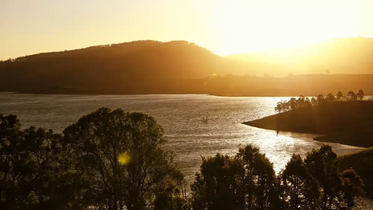 Sunset over Lake St Clair NSW with calm water and surrounding hills