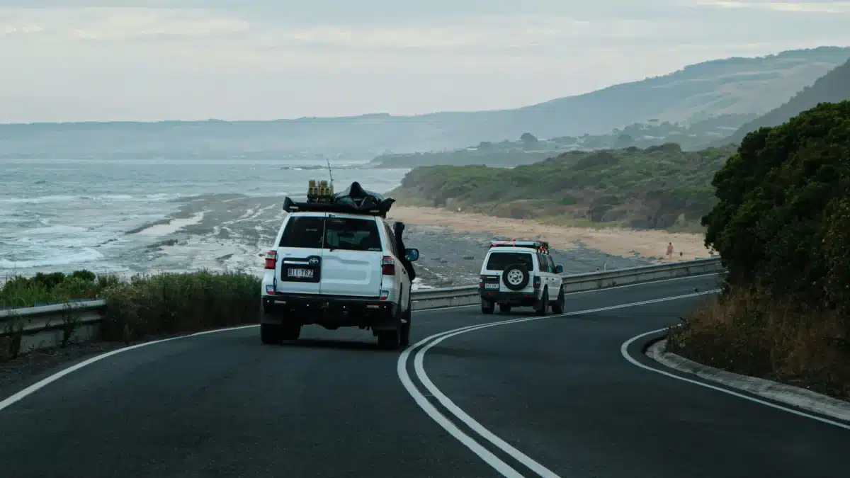 two 4wd driving along coastal road to an off-grid campsite