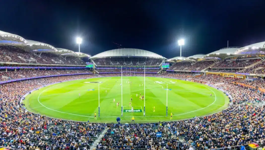 AFL-Gather-Round-south-australia-2026 large afl stadium filled with people wide view lights on at night