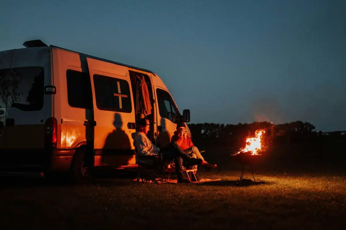 couple sitting outside camping with fire