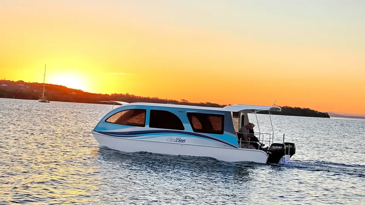 Caravan–boat hybrid travelling on open water at sunset, reflecting changing touring setups as some travellers rethink owning both a caravan and a boat.