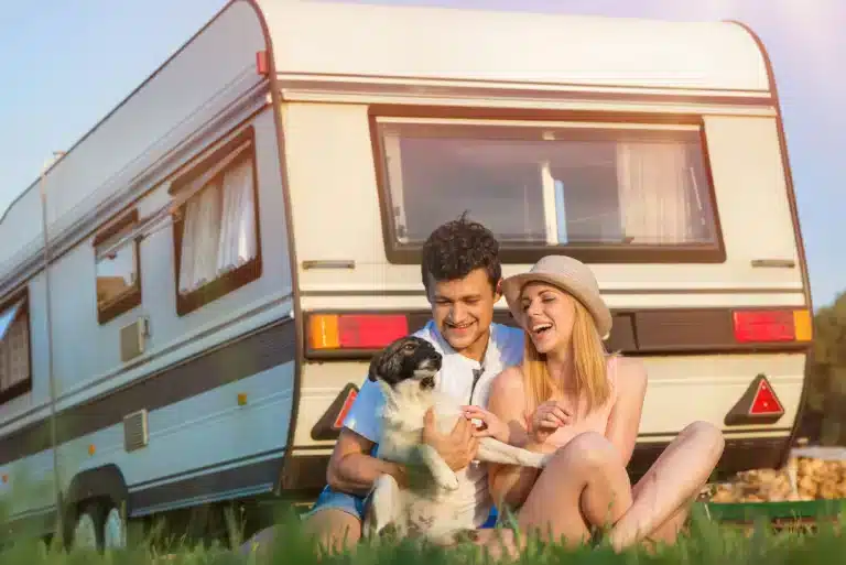 couple happy with dog beside caravan