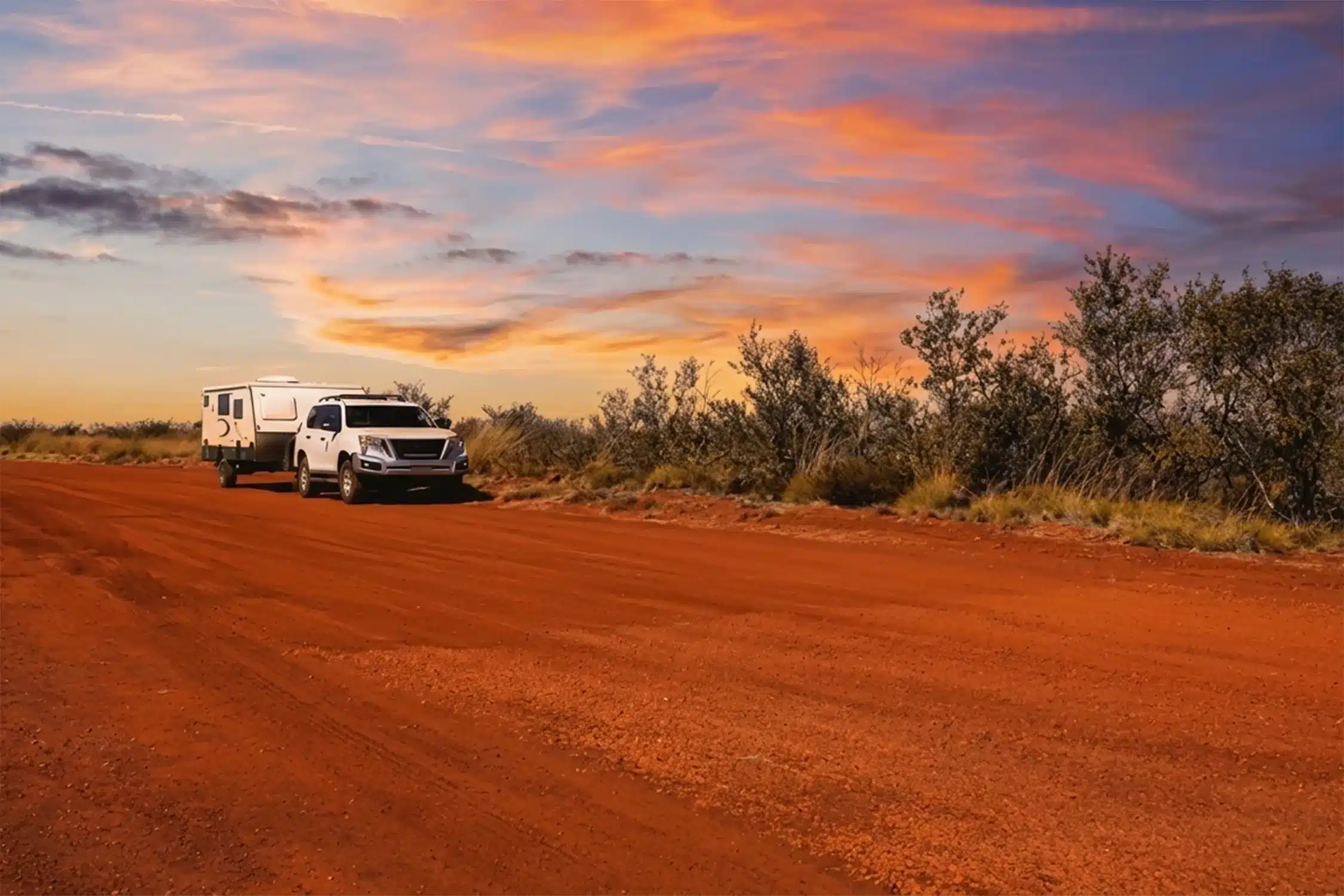 caravanner on australian outback road at sunset