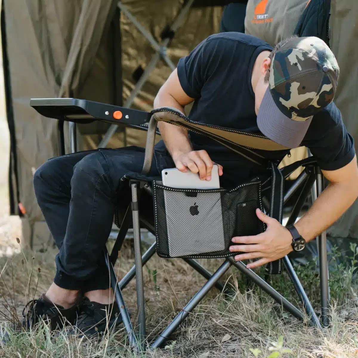 man putting ipad into camp chair pocket