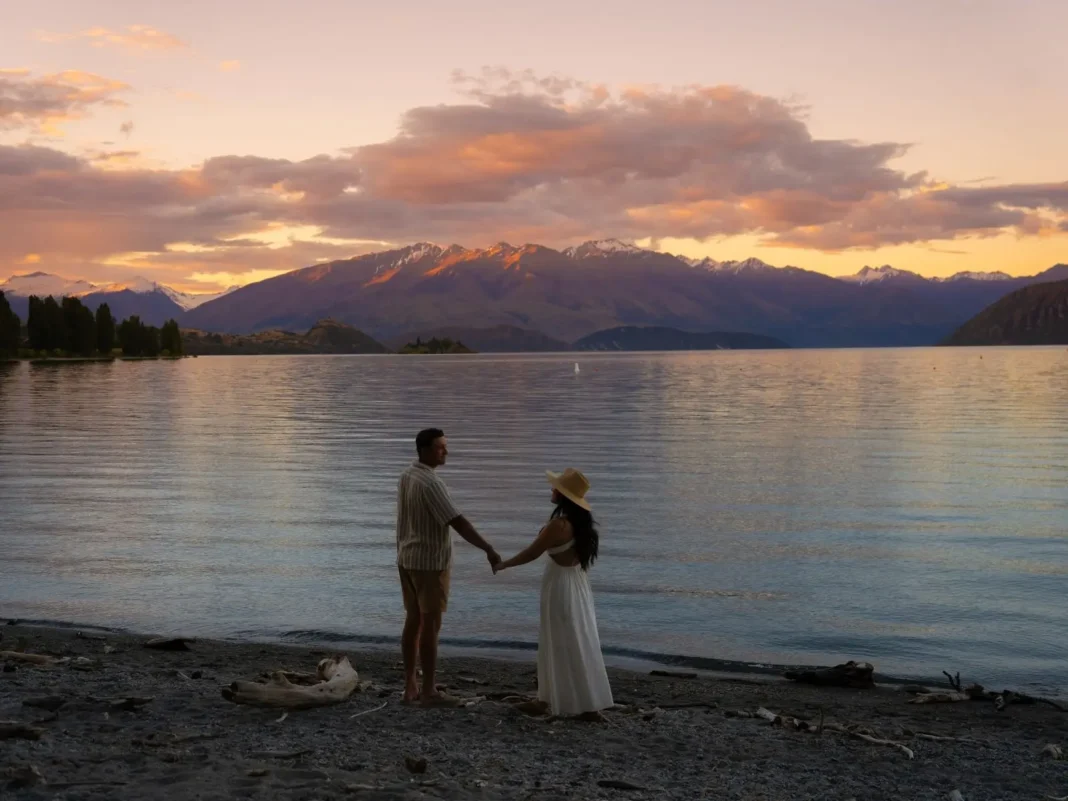 couple standing at lake with mountain in background