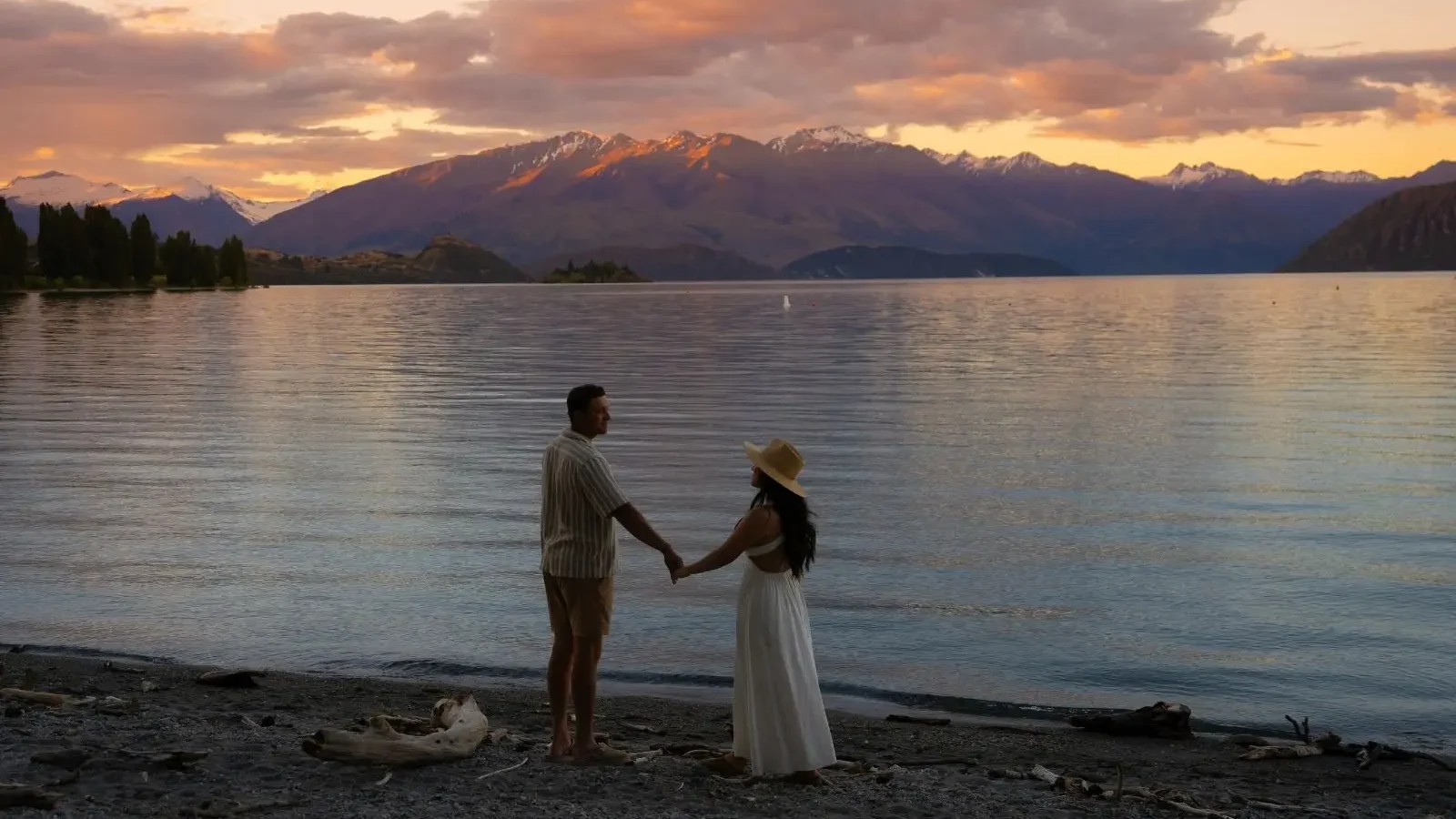 couple standing at lake with mountain in background