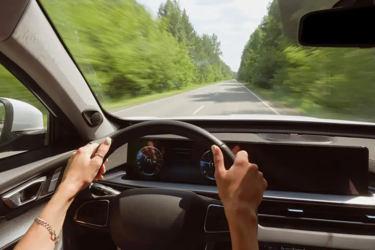 car driving at speed in the forrest with green trees
