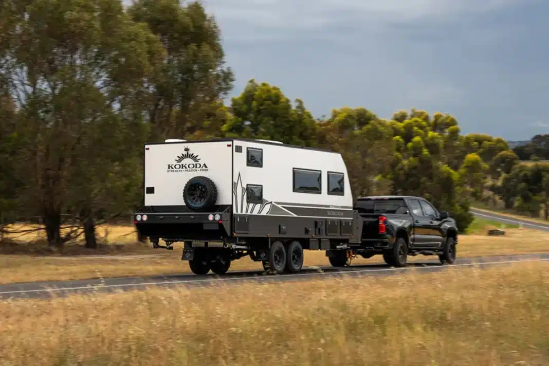 kokoda caravan being towed on road with trees and grass