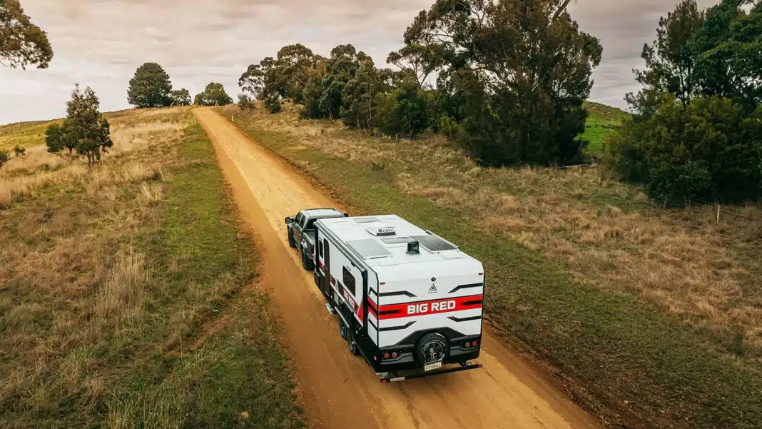 caravan-towing-country-road-australia Caravan being towed along a regional dirt road in Australia during a road trip affordable Easter caravan holidays