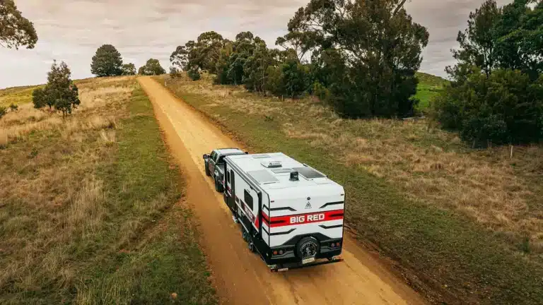 Caravan being towed along a regional dirt road in Australia during a road trip affordable Easter caravan holidays
