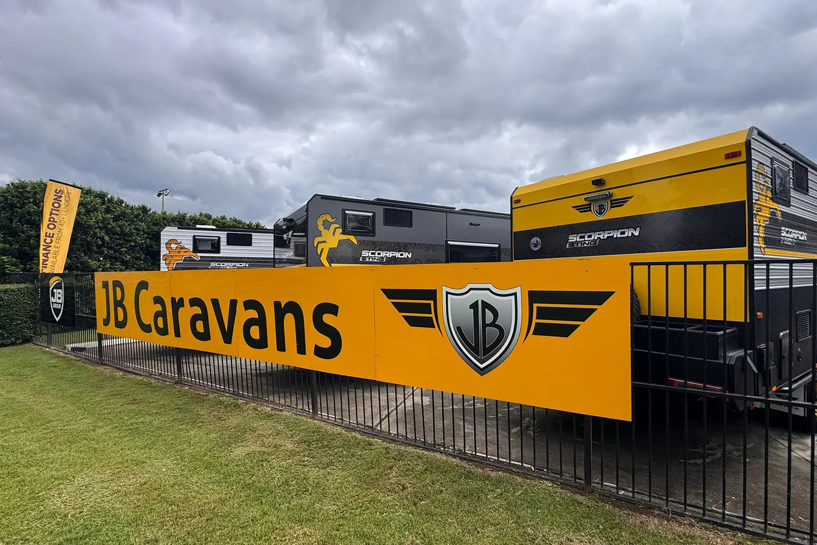 JB Caravans dealership signage at Sydney RV Penrith with Scorpion Sting caravans behind fence.