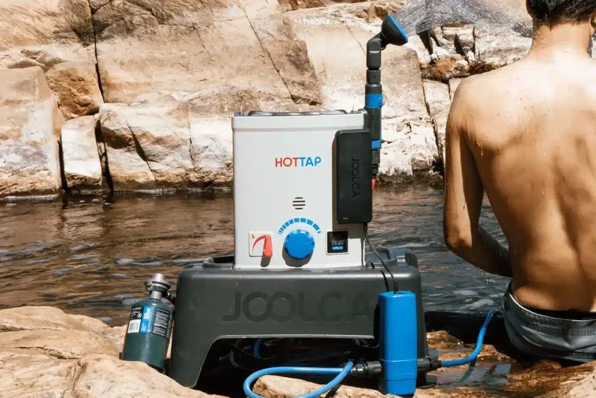 Joolca HOTTAP V2 portable hot water system used for outdoor shower by river campsite