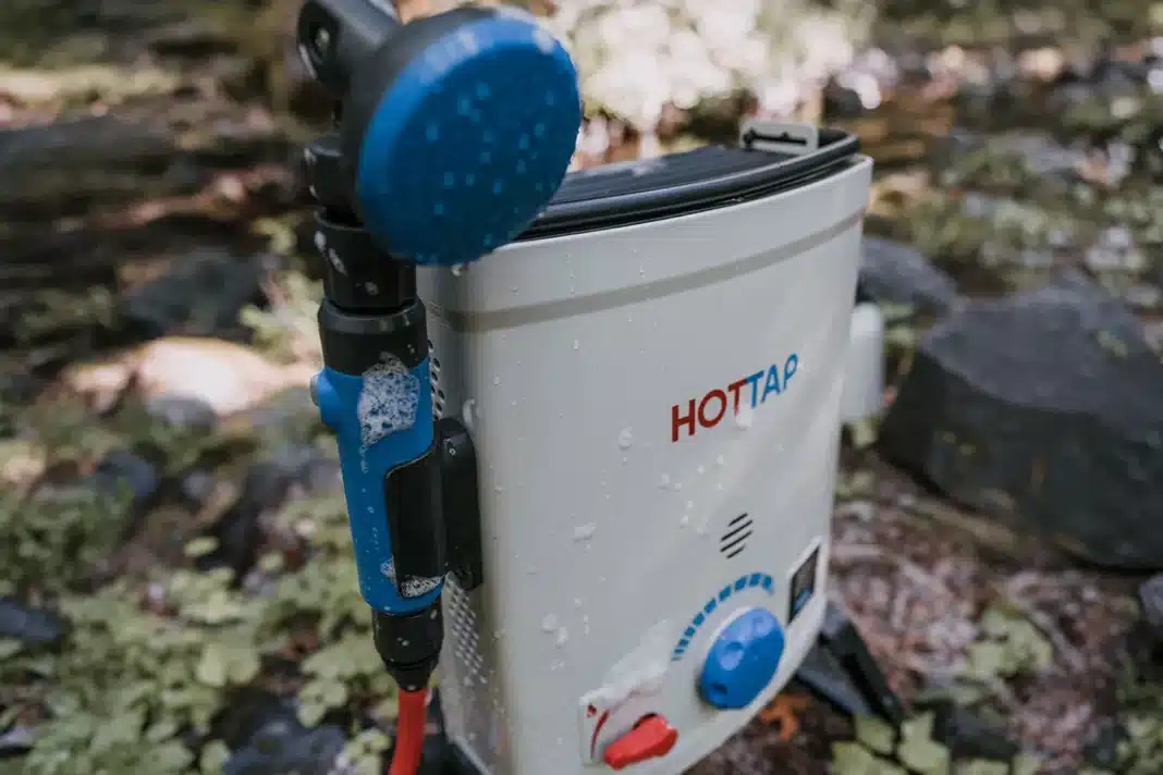 Close-up of Joolca HOTTAP V2 portable hot water system with shower head attached