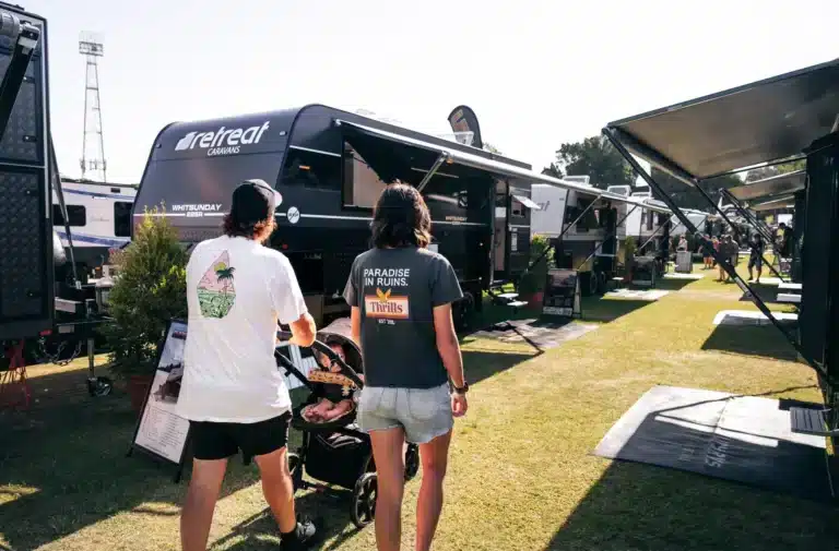 Visitors walking past caravans on display at an Australian caravan and camping show.