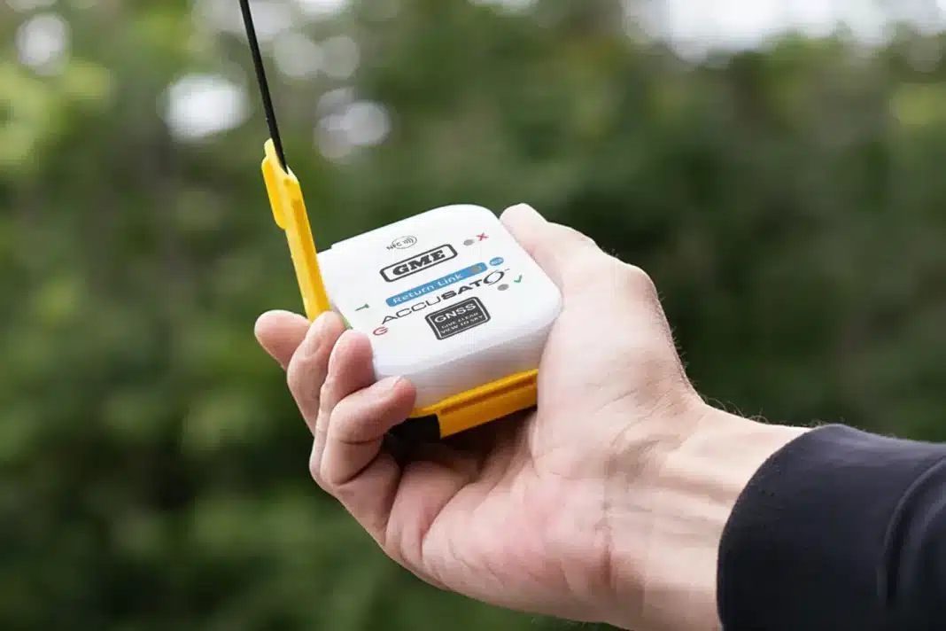 gme-mt620gr-plb-hand-antenna-extended-outdoors Hand holding an activated GME MT620GR personal locator beacon with antenna extended against a green bush backdrop