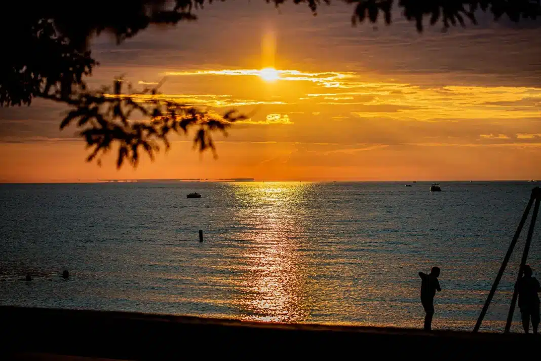 mindil-beach-sunset-darwin-northern-territory Mindil Beach in Darwin at sunset during the dry season, with orange and pink sky reflected on the water and silhouettes of visitors on the sand.