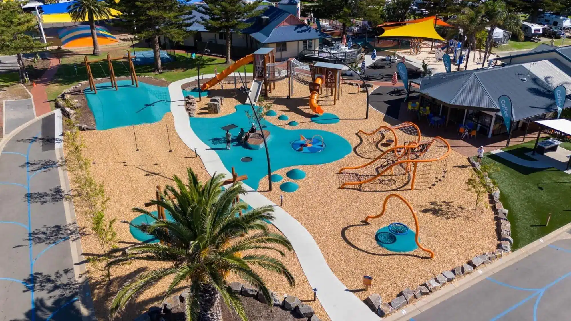 Aerial view of a large, modern children's playground and cafe facilities at an Australian family holiday park.