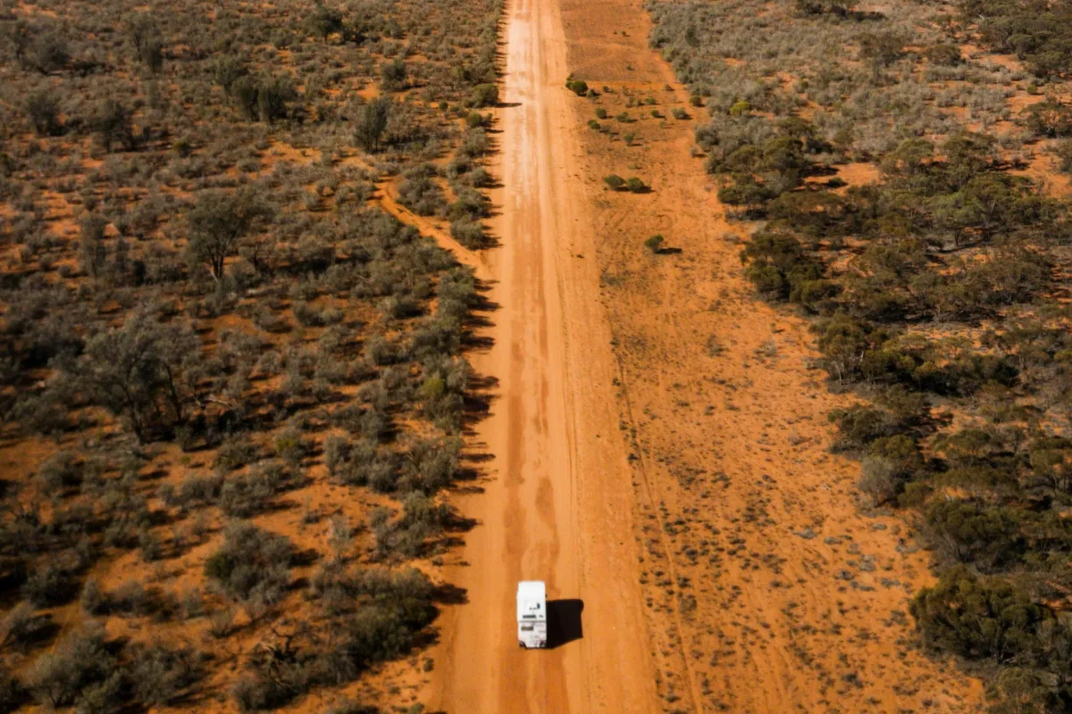 motorhome on red dirst road with shrubs