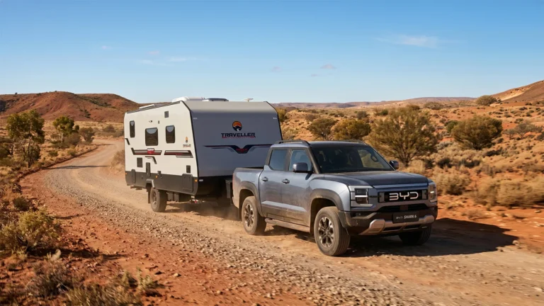 BYD Shark 6 PHEV ute towing a caravan on an outback dirt road in Australia