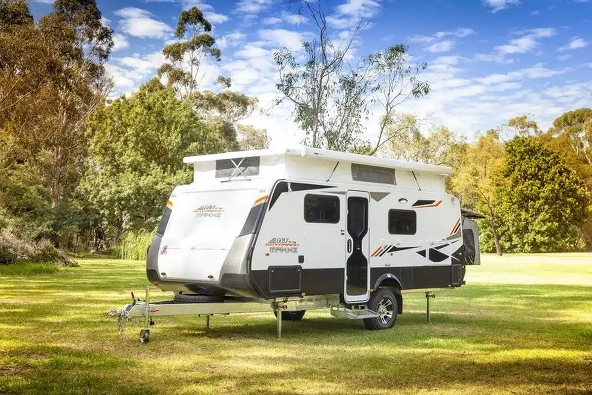 Golf Savannah Maxxi pop-top caravan set up on grass in an Australian bush setting, showing the raised pop-top roof, full-height entry door, and compact single-axle profile