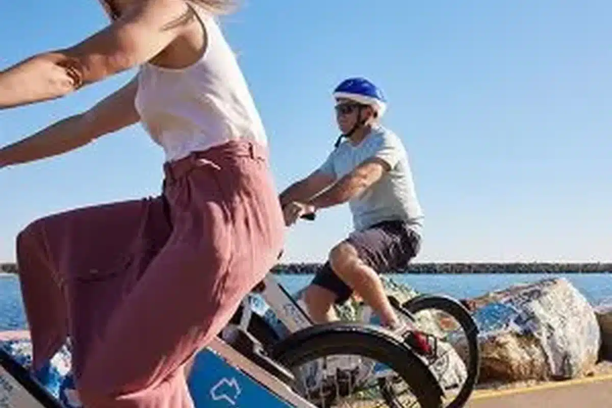 Couple riding bikes along the waterfront at an NRMA holiday park with blue ocean views in the background