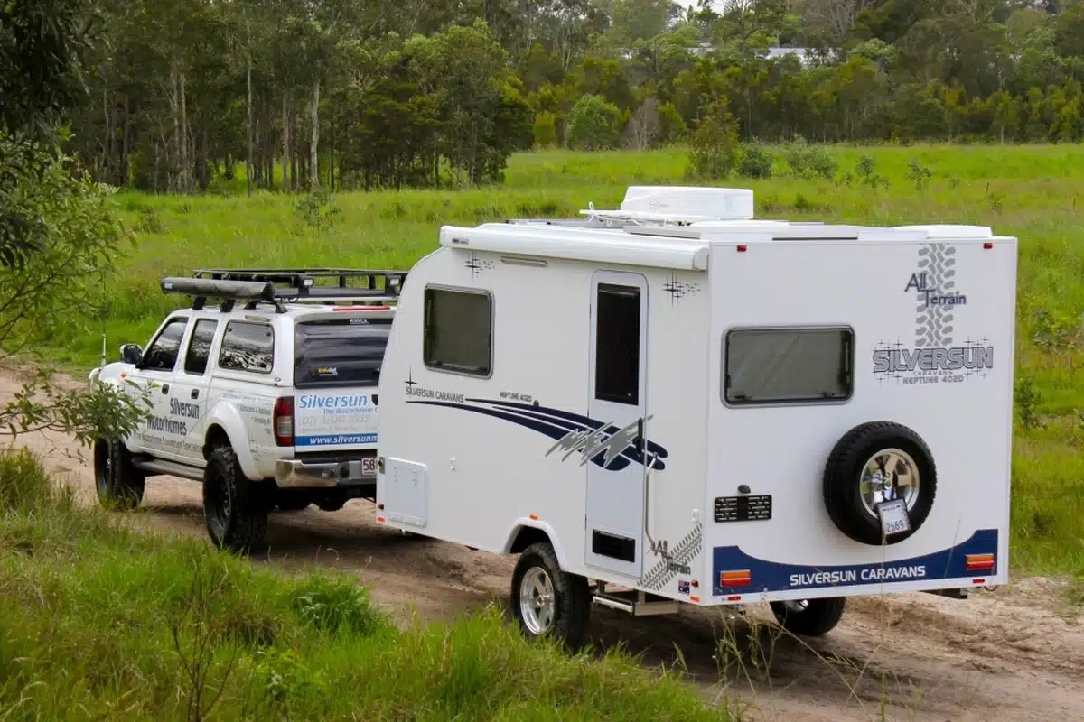 Silversun Neptune 402 All Terrain compact caravan being towed by a white 4WD on a Queensland gravel track, showing the van's full-height Australian-made construction