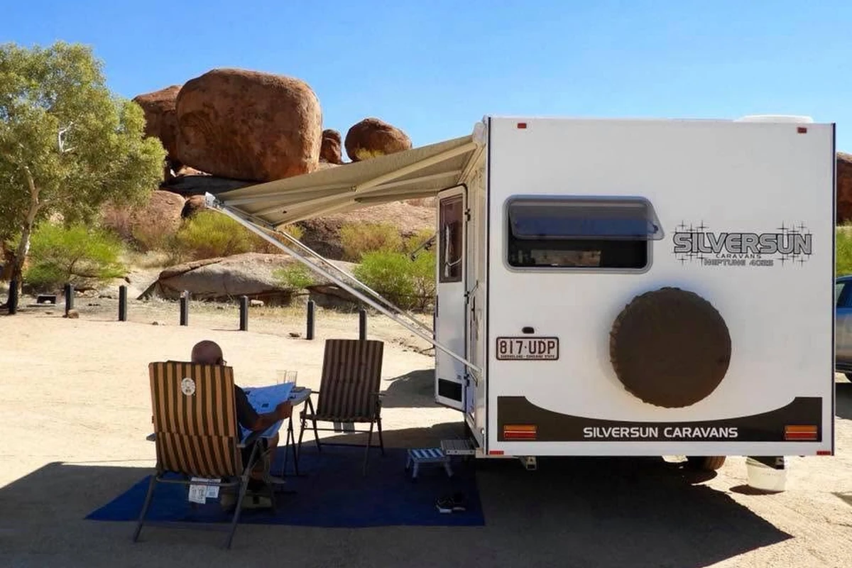 Silversun Neptune caravan set up at Devils Marbles in the Northern Territory, awning out and camp chairs under the iconic red rock outback landscape