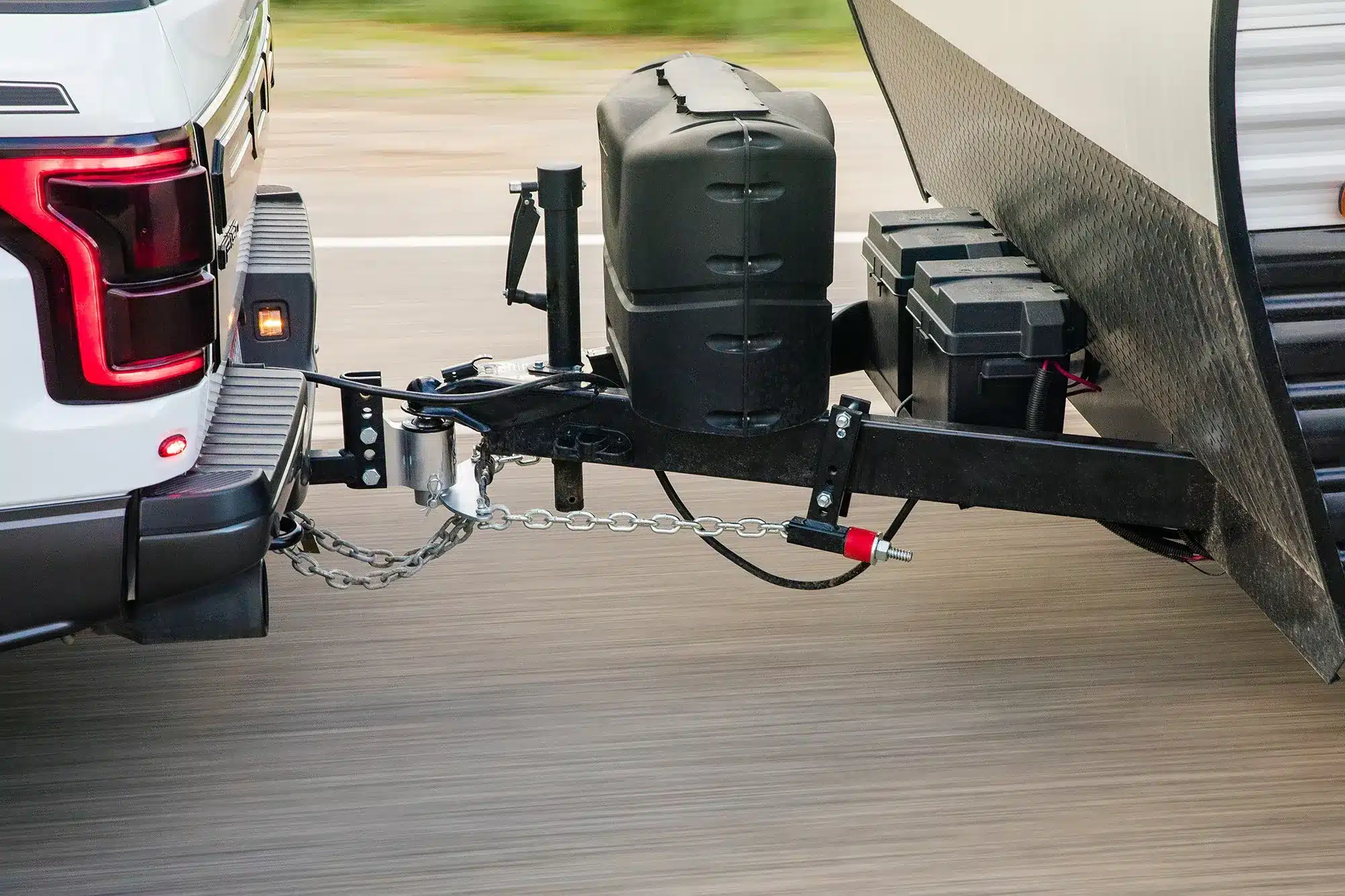 Weight distribution hitch and sway control bar connecting a tow vehicle to a caravan while travelling on the road