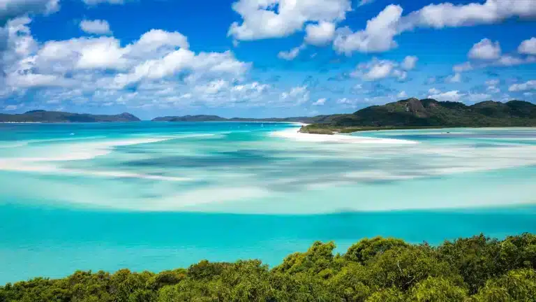 whitsunday-island-aerial-view.webpAerial view of Whitehaven Beach on Whitsunday Island, showing the iconic white silica sand, swirling turquoise channels, and surrounding national park