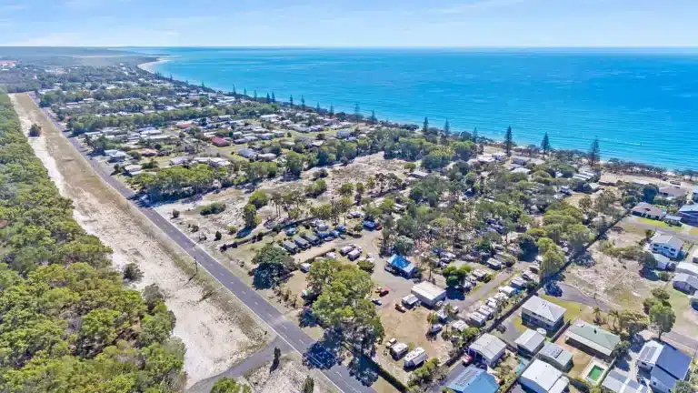 Aerial drone view of NRMA Woodgate Beach Holiday Park showing the park positioned between Burrum Coast National Park and the ocean, Fraser Coast Queensland