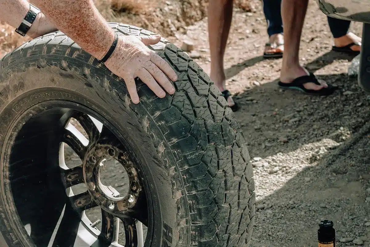 Close-up of hand checking off-road caravan tyre tread and sidewall condition