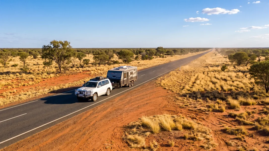 outtback-travel Aerial view of a white 4WD towing a caravan along a sealed outback highway, surrounded by red dirt and spinifex grassland.