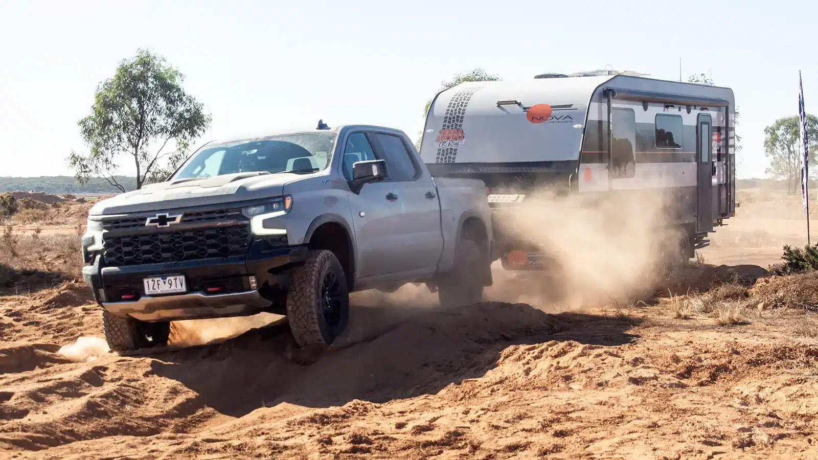 Chevrolet Silverado towing a Nova off road caravan through deep bulldust on a sandy outback track