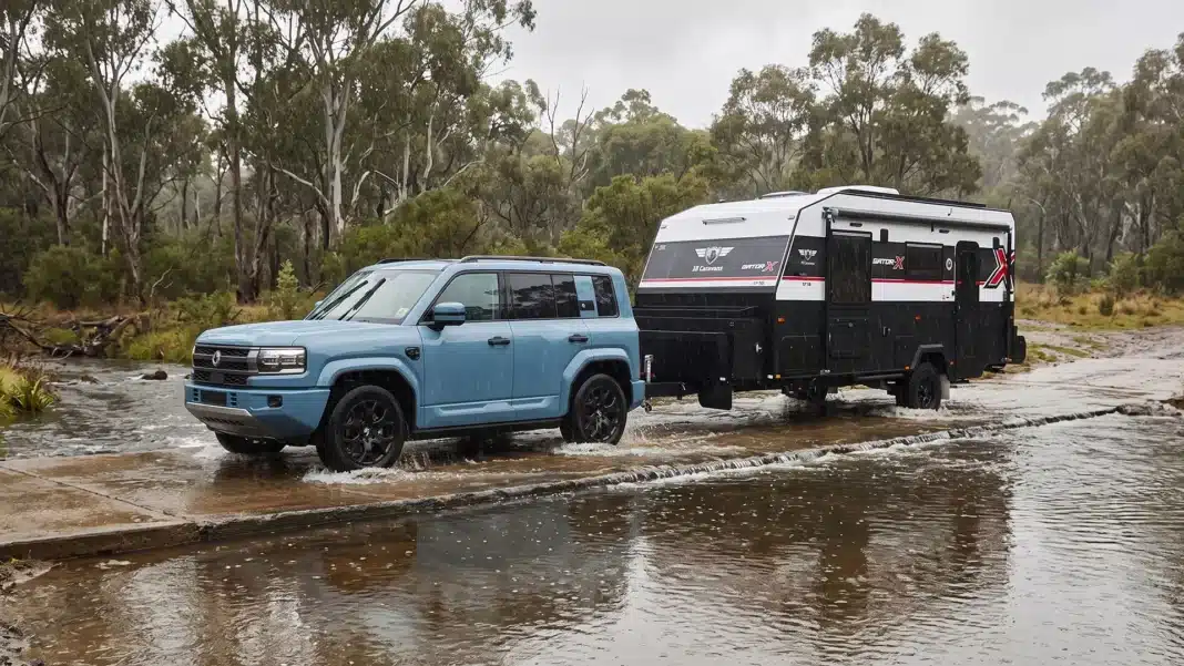 denza-towing-jb-caravan-in-flood 4WD towing an off road caravan through a shallow flooded creek crossing in heavy rain on an Australian bush track