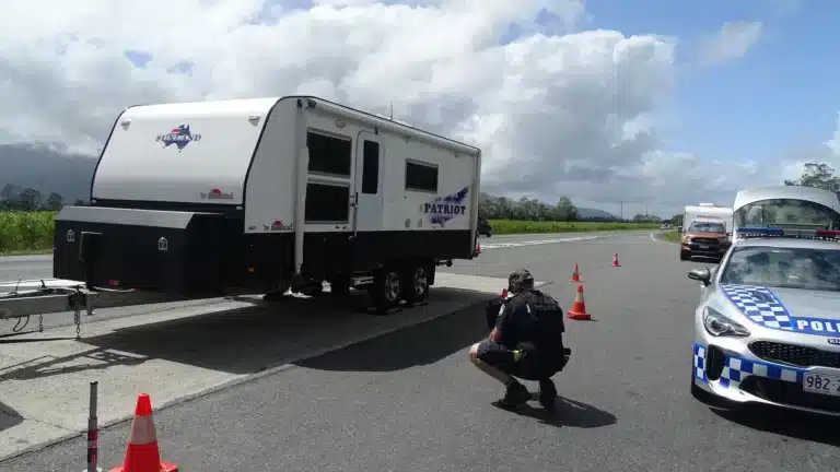 Police officer inspecting a Sunland Patriot caravan's weight at a roadside checkpoint
