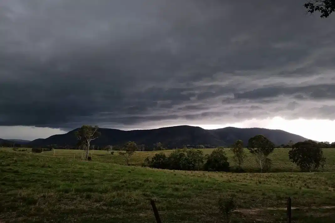 storm-clouds-above-mountains-aus Dark storm clouds building over green farmland and hills in regional Australia ahead of a severe thunderstorm warning