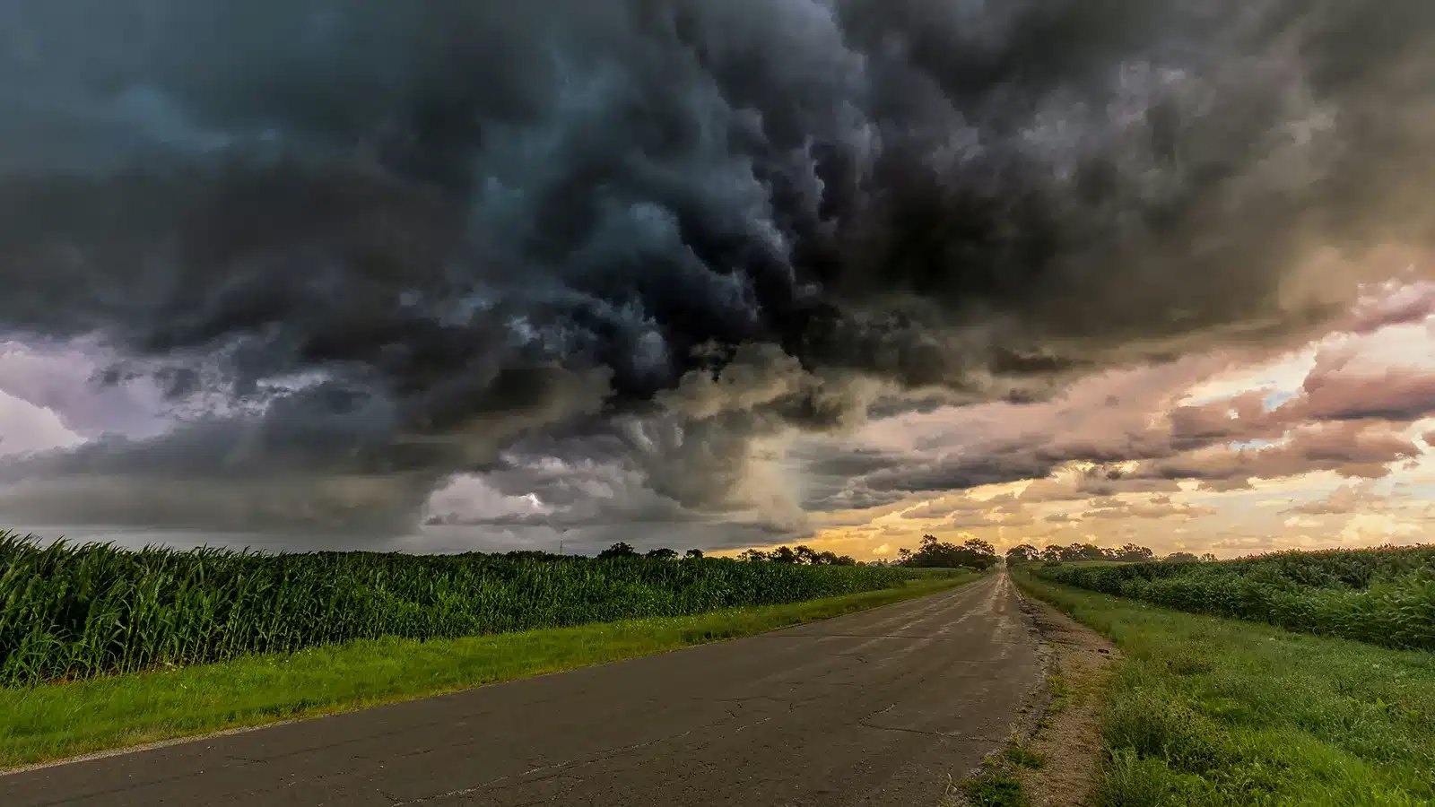 Heavy storm cloud rolling over an open country road at sunset, the kind of conditions that make towing a caravan unsafe