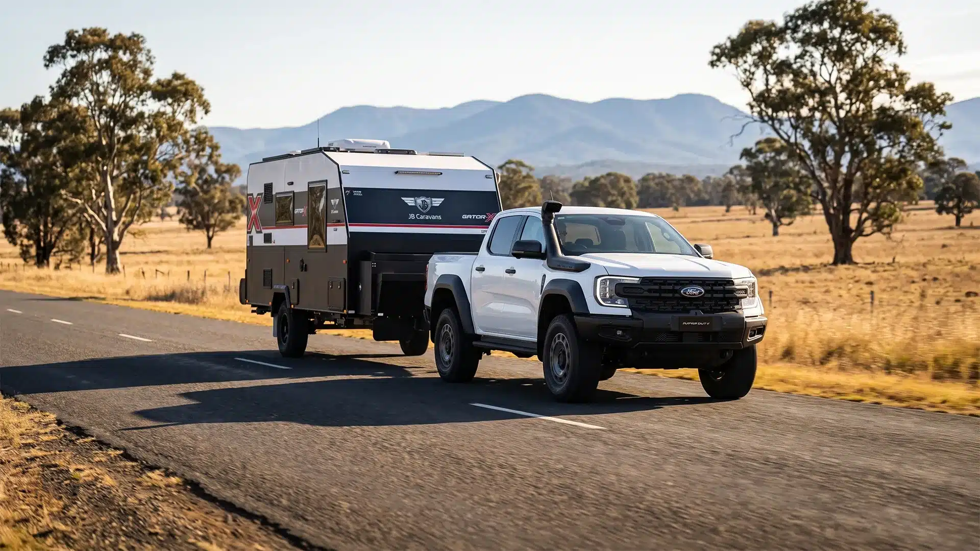 Ford Super Duty towing a JB Caravans Gator X off-road caravan on a country road